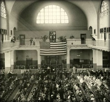 Detail from photo of immigrants seated on long benches, Main Hall, U.S. Immigration Station, date unknown; New York Public Library Digital Collection