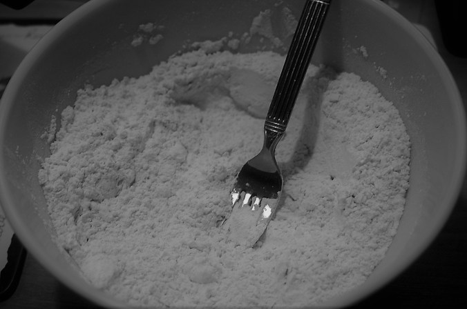 Vintage glass mixing bowl with flour and fork, just cutting in the shortening