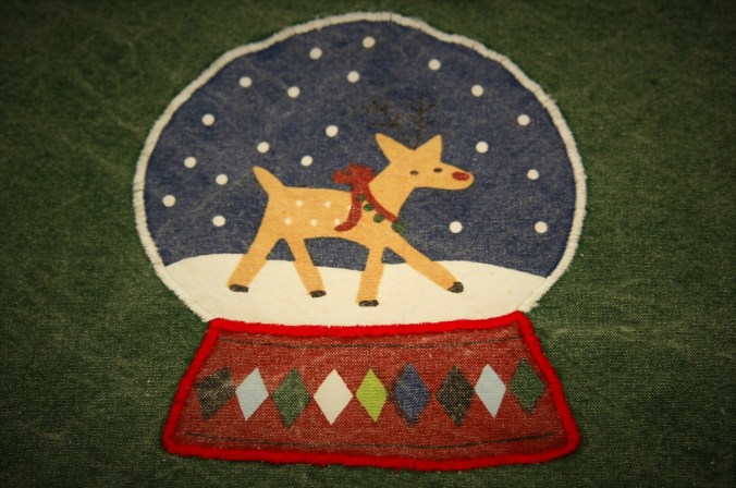 Detail of reindeer in snow globe on denim Christmas placemat